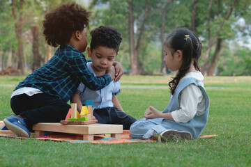 Dark skinned boy hugged and comforted his little friend, group of multi-ethnic kids in park, little girl looked closely, warm relationship between children