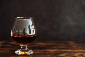 cognac in a glass on a dark background on a wooden table