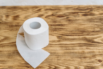 a roll of white toilet paper on a wooden background copy the space. the concept of hygiene products