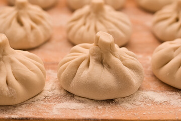 Focused image of raw khinkali on a wooden board side view.