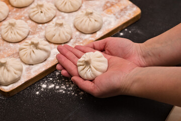 Freshly molded traditional Georgian khinkali from dough with minced meat and spices on the chef's palms.