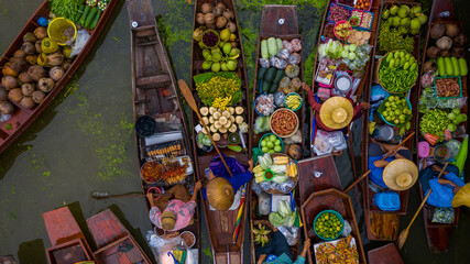 Obraz premium Aerial view famous floating market in Thailand, Damnoen Saduak floating market, Farmer go to sell organic products, fruits, vegetables and Thai cuisine, Tourists visiting by boat, Ratchaburi, Thailand