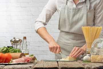 Chef cuts parmesan cheese on a light background, for italian pasta.Culinary recipes, home cooking.