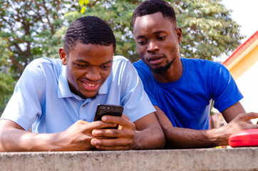 two handsome african feeling excited about what they saw on their cellphone