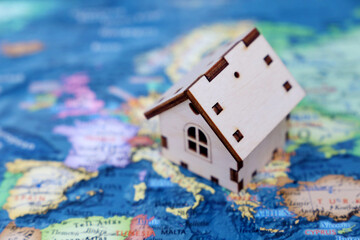 Wooden house model on background of Europe map. European housing market, purchase or rental of real estate in EU