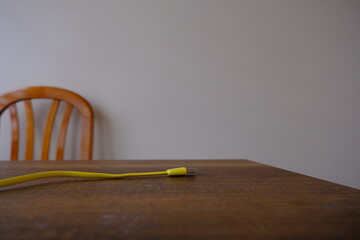 Yellow colored USB type cable staying on dark wooden table.