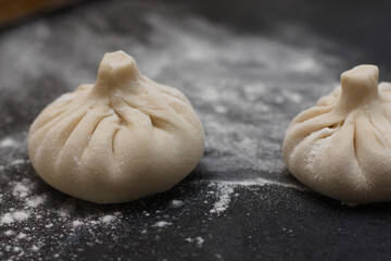 Raw Georgian khinkali in flour on a table. Side view