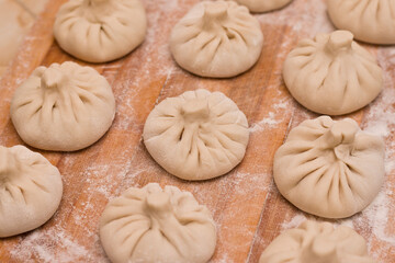 Rows of raw georgian dish khinkali cuisine on wooden board with flour