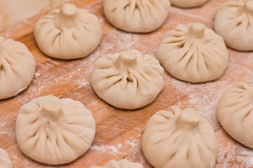 Raw khinkali staggered. Georgian cuisine dish on wooden board with flour