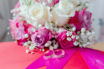 Wedding bridal bouquet of white and red roses and two wedding rings lie on a red pillow 