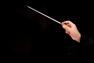 Woman hand holding Baton or Magic wand conjured up in the air. on black background, Miracle magical...