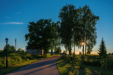 Fototapeta na wymiar Magnificent nature, Russian birch trees surround the entrance to the monastery in the rays of the setting sun. Holy Trinity Alexander Svirsky Monastery in the Leningrad region.