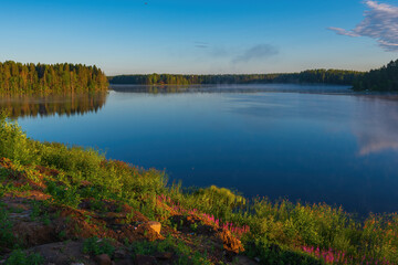 Picturesque places of the Roshchinsky lake near the walls of the monastery at sunrise. Holy Trinity Alexander Svirsky Monastery in the Leningrad region, known for architectural monuments.