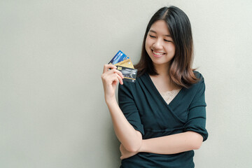 Asian beautiful woman Wearing a black shirt Have a credit card in hand Happy face Standing in the gray wall