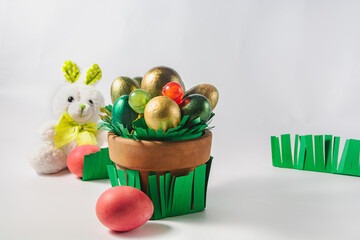 White Easter bunny, a pot of colored eggs and sweets are on a white background. Easter holiday concept