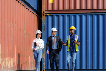African american foreman is explaining the various sections of the container depot terminal to a caucasian man manager, with a female secretary next to him.