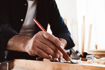 Carpenter makes pencil marks on a wood plank