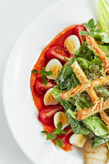 Caesar salad with bread sticks, quail eggs, cherry tomatoes and grilled chicken in plate on white background