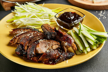 Peking duck chinese food. Yellow plate with vegetables and sauce on dark slate table. Chinese, asian, authentic food concept