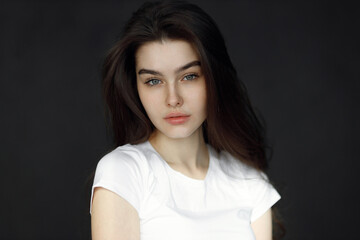 Fototapeta premium Close-up portrait of a young beautiful woman, on a dark background. Beauty portrait of a girl, studio tests.