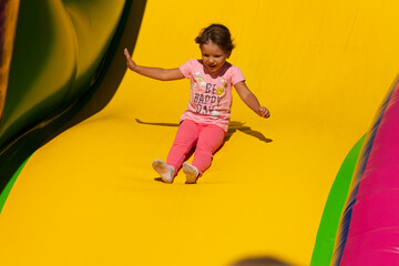 The child descends from a large inflatable slide