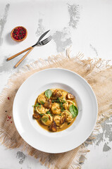 Dumplings Food Restaurant Plate. Dumplings With Creamy Porcini Sauce. White restaurant plate on white table. Rustic restaurant food concept.