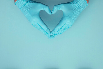 Doctors hands wearing blue surgical gloves making hear shape symbol.