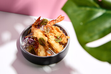 Restaurant seafood - Tempura shrimp & almond and cabbage salad. Appetizer food plate on white table with pink wall. Day sunlight with hard shadow of monstera palm leaves. Summer, spring food concept.