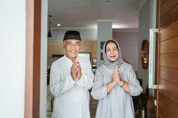 portrait of muslim asian senior couple standing at front door waiting for family to come