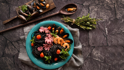 Seafood pasta with shellfish and shrimp. Spaghetti Vongole in a black pan on a natural stone background. Top view. Copy the space.
