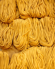 Vertical closeup on strops of dry egg noodle nests texture