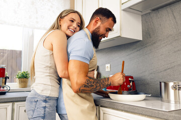 Young man and woman cooking food in kitchen together, happy couple preparing food