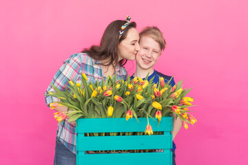 Family portrait sister and teenager brother with tulips on pink background