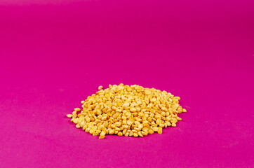 Dry yellow peas on a pink background.