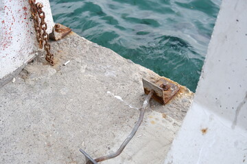 Smoked cigarette and put out on the street ground with its ashes near the turquoise color bosporus sea in istanbul together with ship tightening metal part and chain that are exposed to corrosion