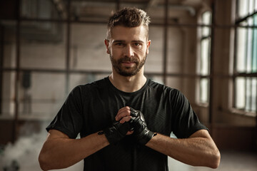 Serious bearded fighter warming up hands before boxing