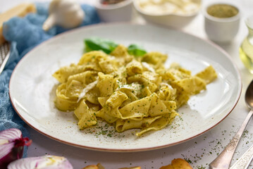 Cooked homemade pasta with pesto, fresh basil, mozarella cheese and herbs