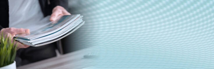 Male hands holding magazines; panoramic banner