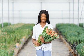 close up of african american woman holding flowers in greenhouse