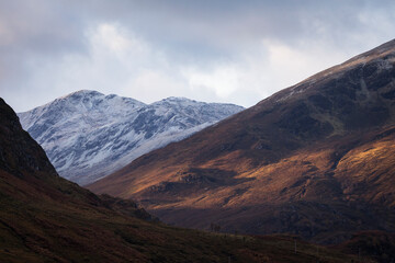 Fototapeta na wymiar Autumn landscape in Highlands, Scotland, United Kingdom. Beautiful mountains with snow in background.