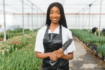 Agriculture management. Smiling african american girl makes photo of flowers plantation in greenhouse, side view, free space