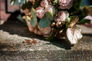 Wedding rings on a stone, a bouquet of pink flowers