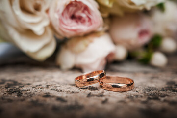 Wedding rings on a stone, a bouquet of pink flowers