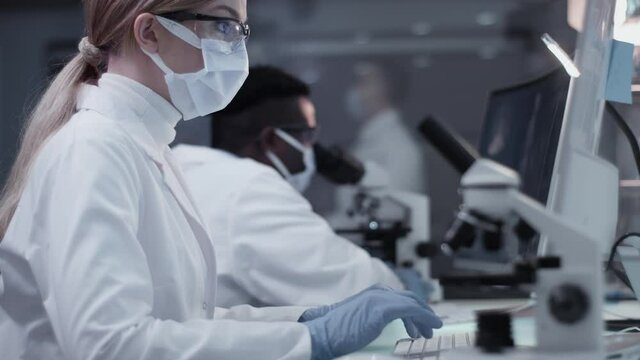 Diverse scientists studying medical samples and human skeleton. Using computers and microscopes. Modern laboratory interior