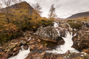 Beautiful Waterfall At Buachaille Etive Mor In The Scottish Highlands with rainy clouds in background..