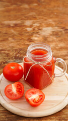 Glass of tomato juice on wooden table. Fresh tomato juice and chopped tomatoes