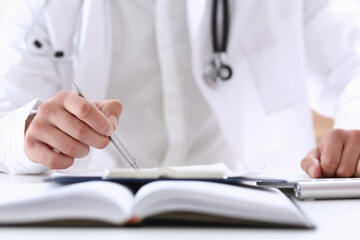 Fototapeta premium Doctor hand hold silver pen filling patient history list at clipboard pad closeup. Physical, exam, er, disease prevention, ward round, visit check, 911, prescribe remedy, healthy lifestyle concept