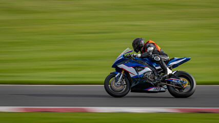 Obraz na płótnie Canvas A panning shot of a racing motorbike as it circuits a track.
