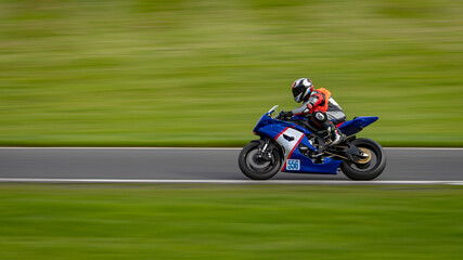 A panning shot of a racing motorbike as it circuits a track.