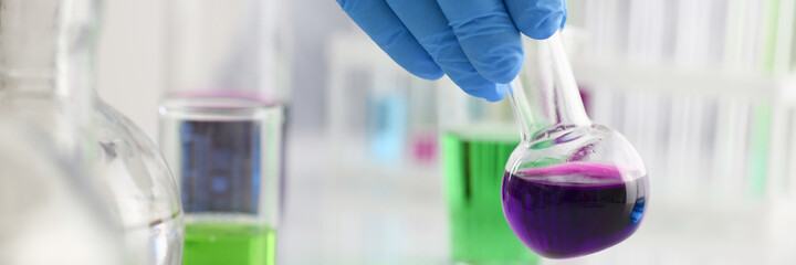 A male chemist holds test tube of glass in his hand overflows a liquid solution of potassium...